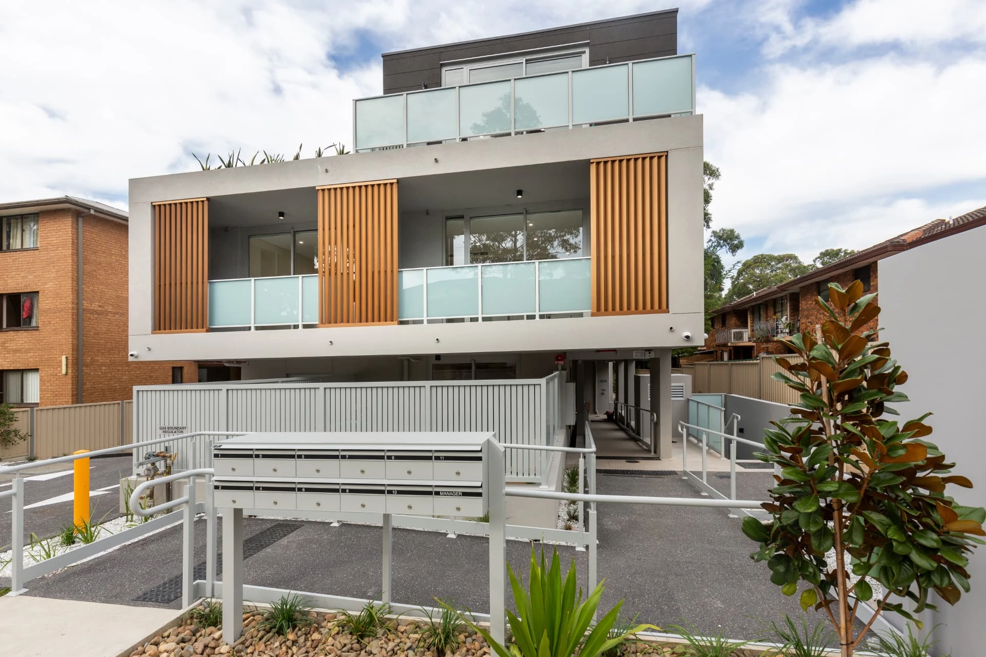 Merrylands Vertical Village, a three storey apartment building with timber screens, planted terraces and a step free entry ramp.